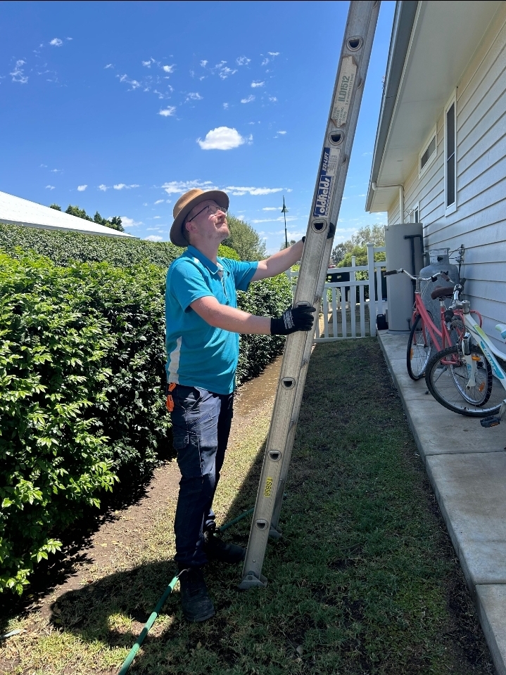 a man climbs up to do gutter cleaning