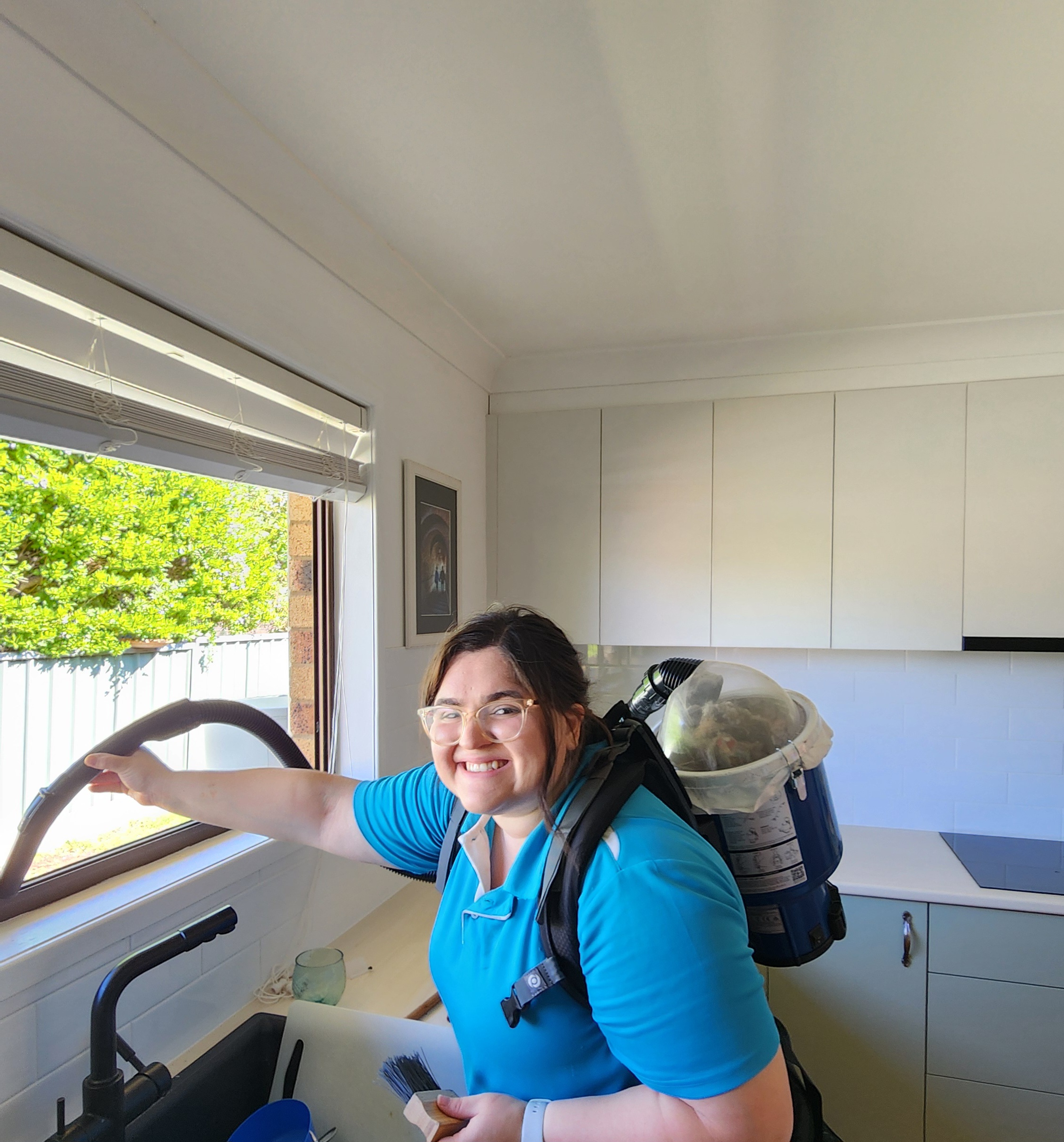 a woman vacuums in a kitchen
